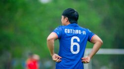 Seorang pemain sepak bola berdiri di lapangan di Hà Nội, Việt Nam, selama pertandingan yang diguyur hujan.