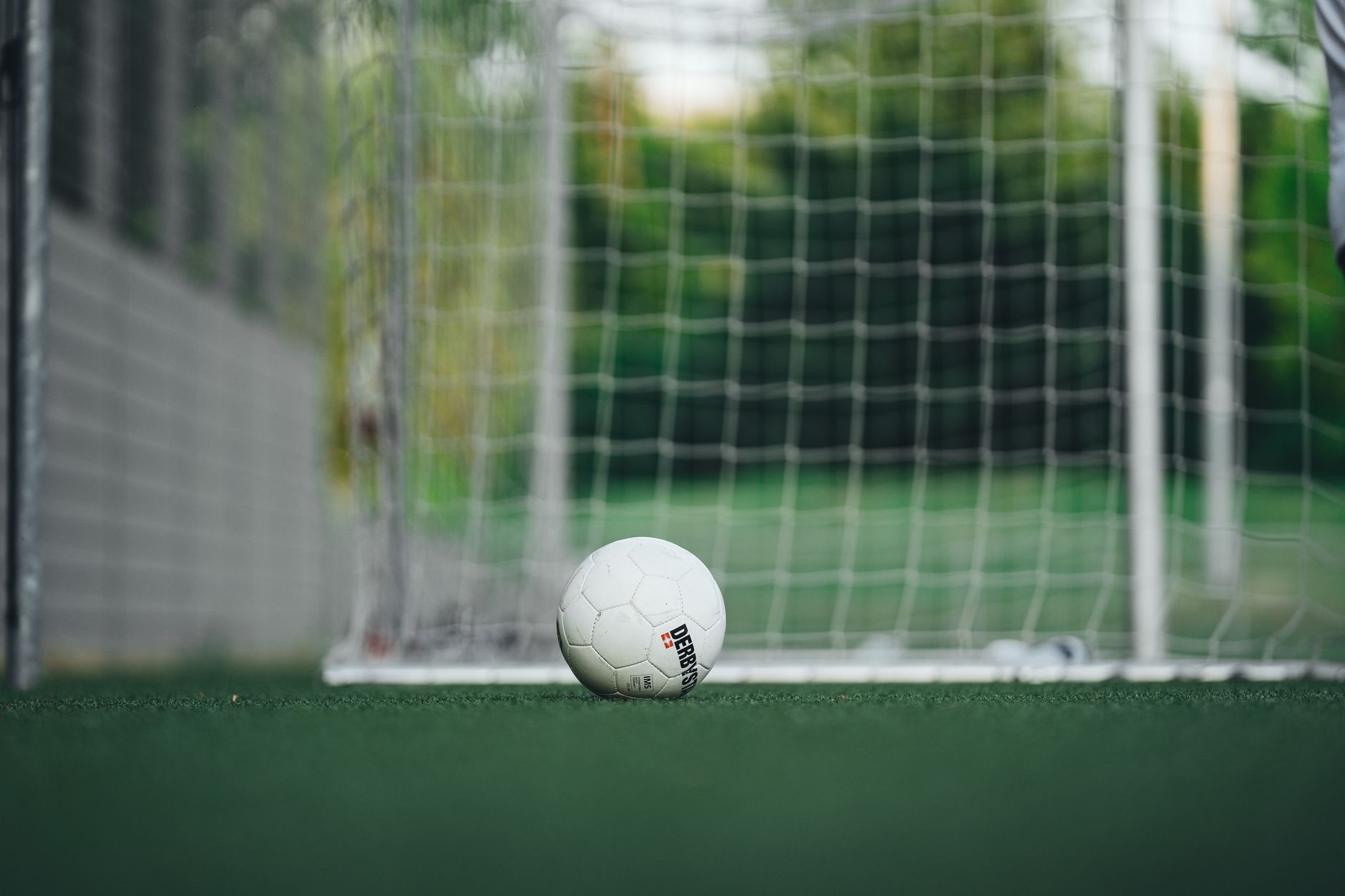 Close-up bola sepak di lapangan luar dengan jaring gawang, sempurna untuk tema olahraga.