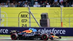 Bidikan dinamis dari mobil F1 yang balapan di Grand Prix Kota Meksiko dengan kerumunan yang bersorak di latar belakang.