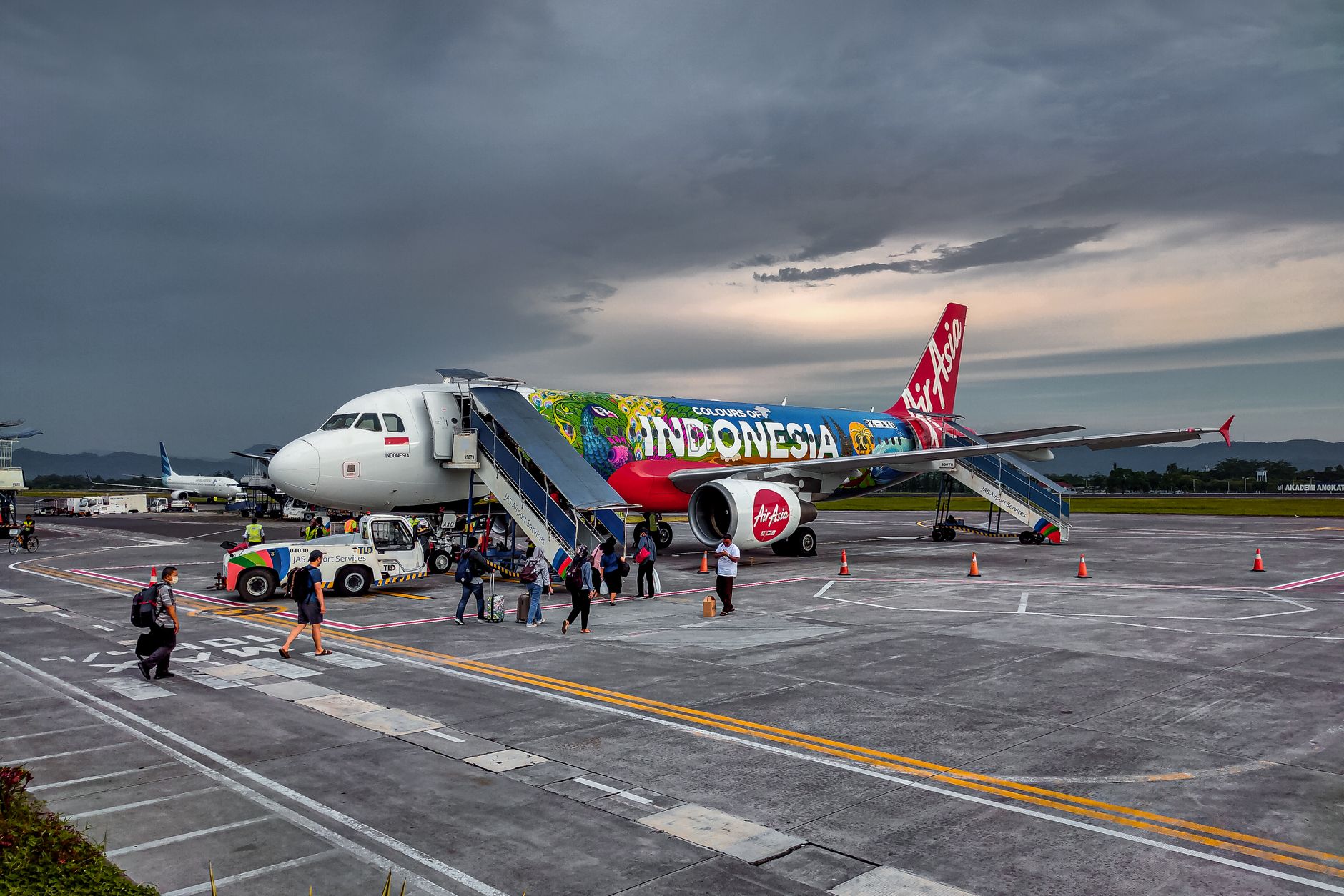 Pesawat Air Asia yang cerah dengan desain bertema Indonesia di Bandara Jogja, menangkap esensi perjalanan.