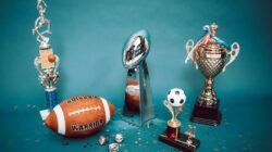 Koleksi trofi olahraga dan barang memorabilia yang mewakili pencapaian dan kesuksesan di latar belakang biru.