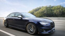 Sedan biru berkinerja tinggi melaju di jalan raya yang indah dengan efek gerakan buram.