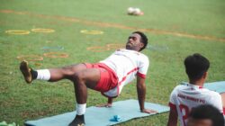 Pemain sepak bola melakukan latihan di lapangan, mempersiapkan diri untuk pertandingan.
