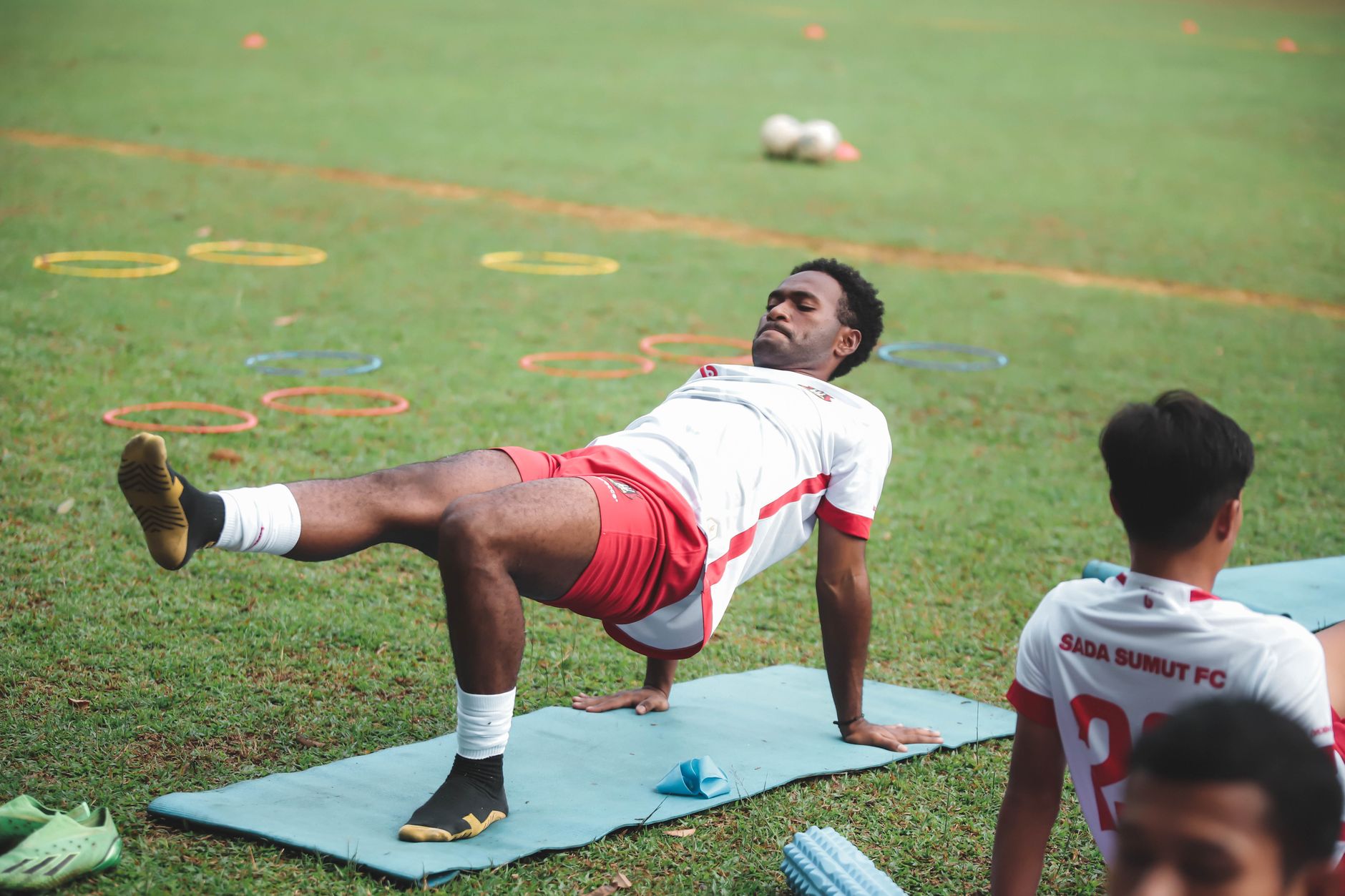 Pemain sepak bola melakukan latihan di lapangan, mempersiapkan diri untuk pertandingan.
