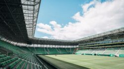 Pemandangan stadion modern di Budapest, Hungaria, dengan kursi hijau dan langit yang luas.