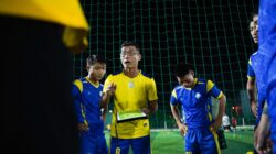Pelatih sepak bola memberikan pembicaraan strategi kepada pemain di lapangan malam.