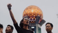 Pria yang memprotes dekat landmark terkenal di Tangerang, Indonesia, dengan tangan terangkat dan gerakan ekspresif.