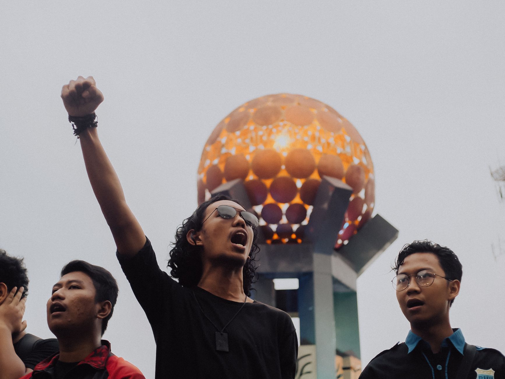 Pria yang memprotes dekat landmark terkenal di Tangerang, Indonesia, dengan tangan terangkat dan gerakan ekspresif.