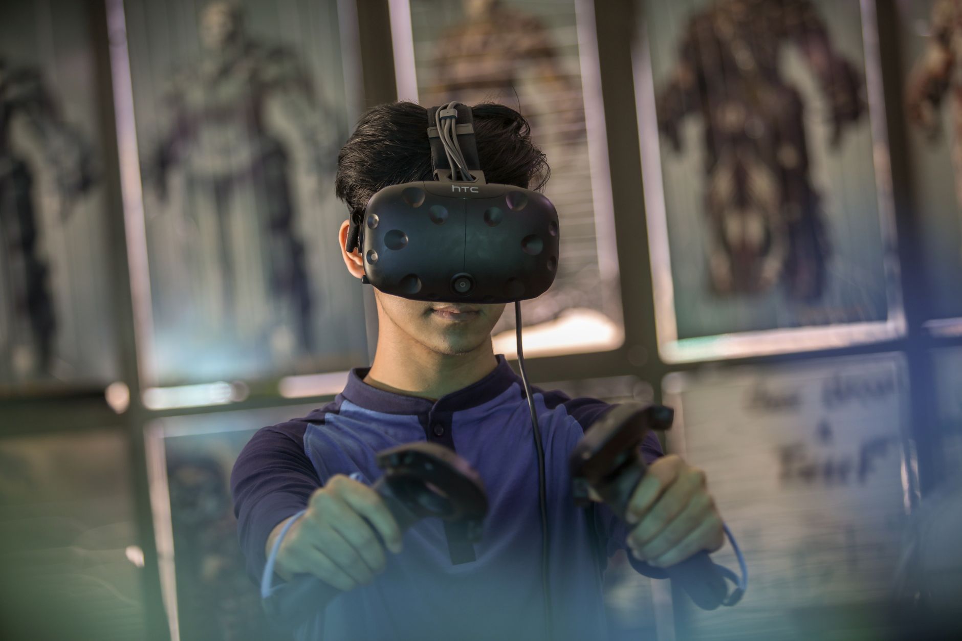 Seorang pria muda menggunakan headset VR dan pengontrol untuk pengalaman bermain yang imersif di dalam ruangan.