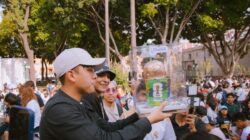 Sekelompok orang merayakan dengan replika trofi FIFA Piala Dunia di lingkungan luar ruangan yang semarak.