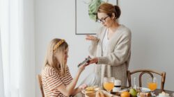 Seorang ibu dan putrinya berdiskusi tentang penggunaan ponsel saat sarapan di rumah.