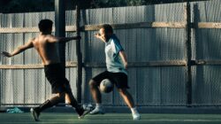 Dua pria terlibat dalam pertandingan sepak bola yang intens, menampilkan aksi dan ketangkasan di luar ruangan.