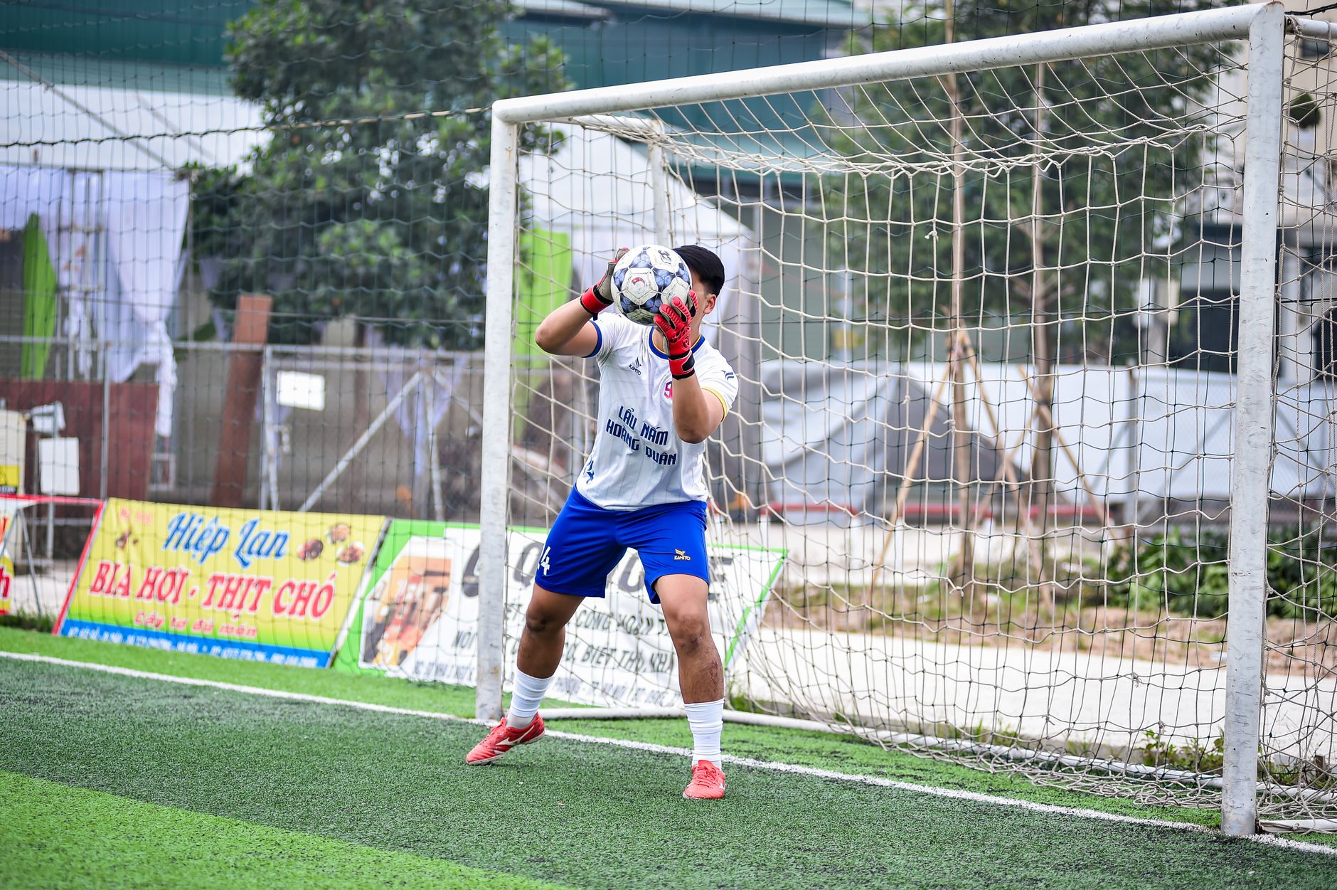 Seorang penjaga gawang melakukan penyelamatan selama pertandingan sepak bola di lapangan rumput buatan di Hanoi, Vietnam.