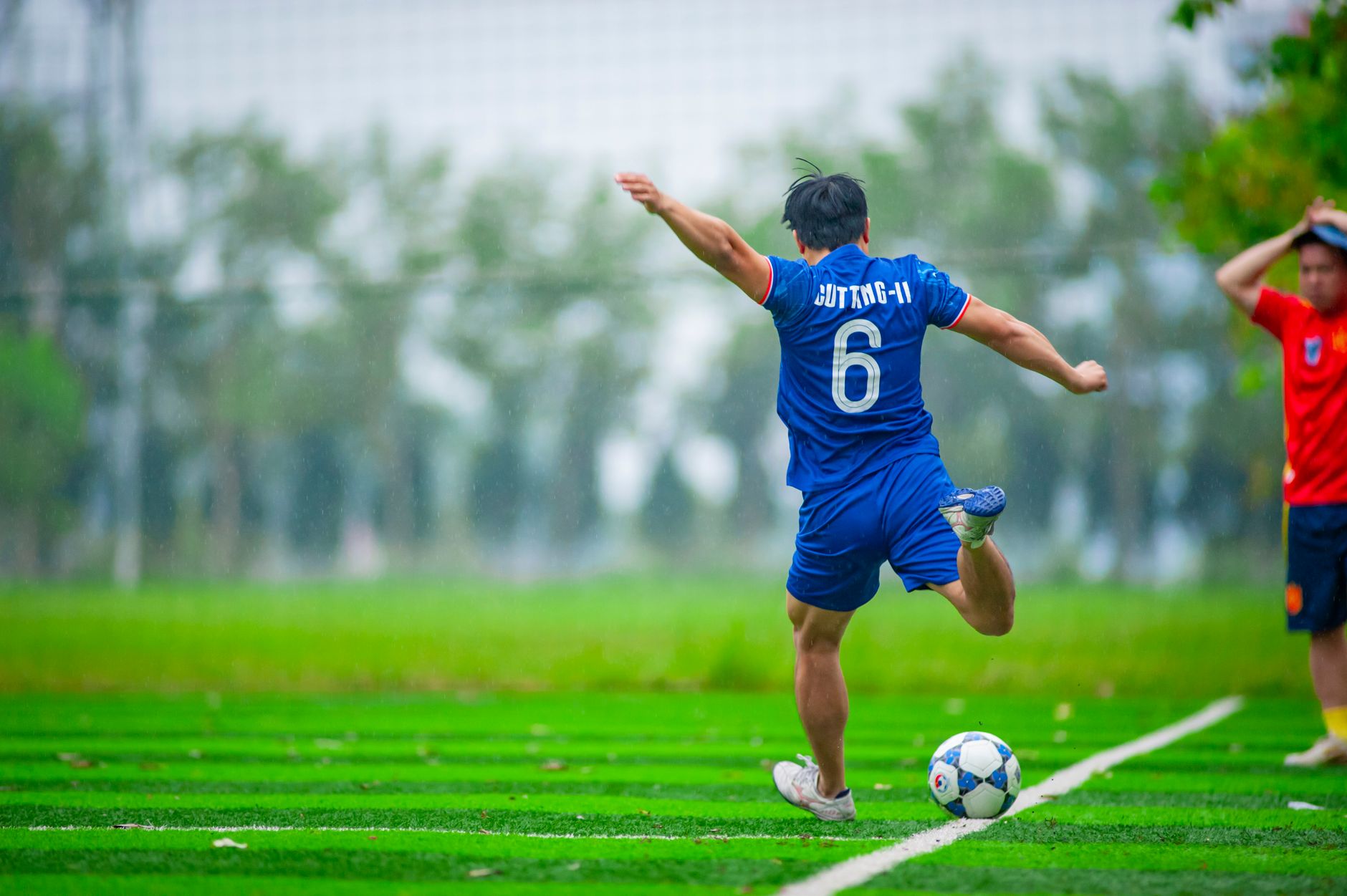 Pemain sepak bola yang energik menendang bola di lapangan hijau di Hanoi, Vietnam.